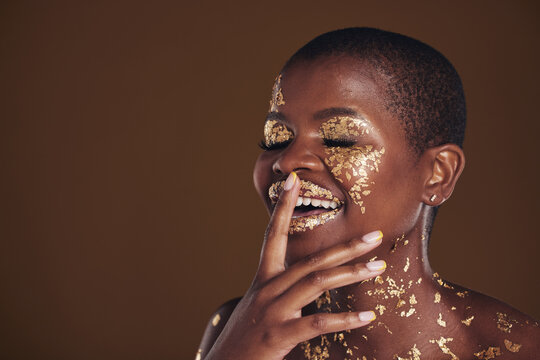 Happy laugh of black woman with gold makeup, mockup on brown background and glitter paint for cosmetics. Shine, glow and smile, African model in studio for facial beauty and funny aesthetic luxury.