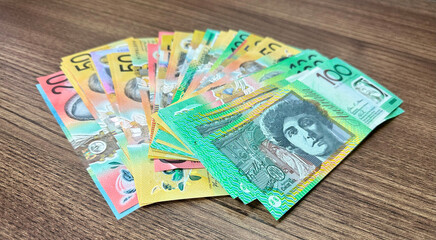 many notes of australian currency on wooden surface background