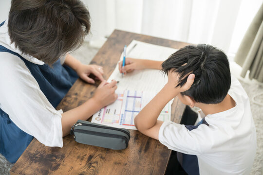 子どもに一生懸命勉強を教える母親