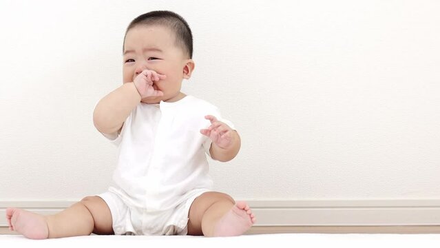 絨毯に座って泣く赤ちゃん（男の子、日本人、生後8か月）