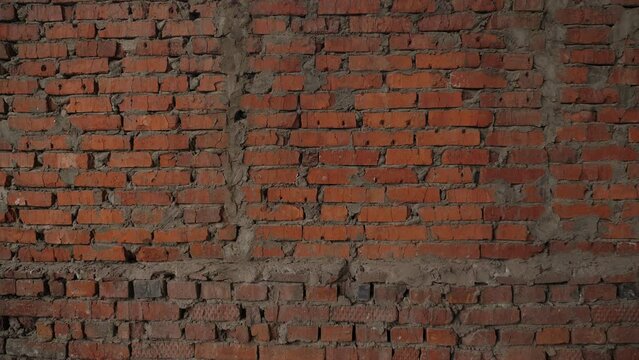 A large brick old wall in an unfinished or destroyed building. Red brick wall, corner of the house. Building. 