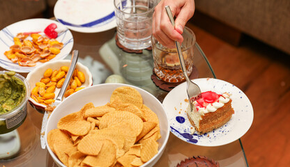 Hands and utensils gather around, embracing the communal spirit of a potluck dinner. Symbolizing unity, sharing, and indulgence as they enjoy a variety of desserts