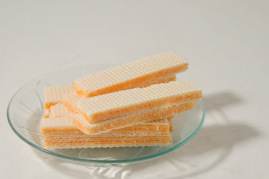 Several wafer biscuits served on a small plate isolated on a white background.
