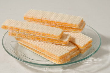Several wafer biscuits served on a small plate isolated on a white background.