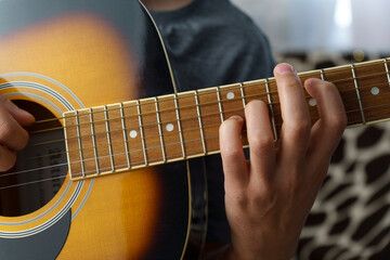 Fototapeta na wymiar Man plays an acoustic guitar at home, close-up. Selective focus