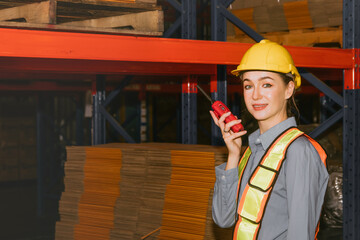 Female workers safety work in the warehouse factory logistics inspect goods stacked on shelves and use walkie talkies to report inspections to effectively communicate with the coordination team.