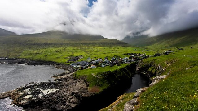 Time lapse of Village of Gjogv on Faroe Islands with colourful houses. Mountain landscape with ocean coast