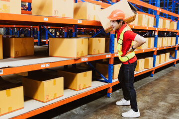 Back pain worker : Asian male worker working in warehouse carrying heavy packing cartons on...