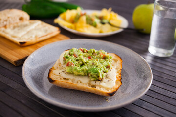 Tasted slices of square bread with warm cheese and homemade guacamole on a plate