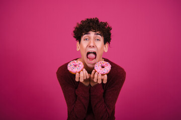 Funny attractive guy eats donuts. Pink background. - obrazy, fototapety, plakaty
