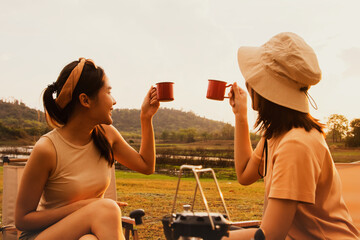 Wonderful evening moment : Two asian female friends sitting and chatting cheerfully drinking...