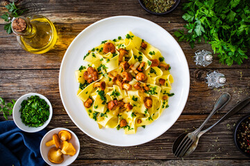Tagliatelle with chanterelle mushrooms on wooden table

