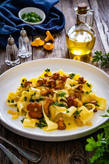 Tagliatelle with chanterelle mushrooms on wooden table
 - obrazy, fototapety, plakaty