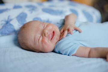 Smiling newborn baby dreaming on the bed