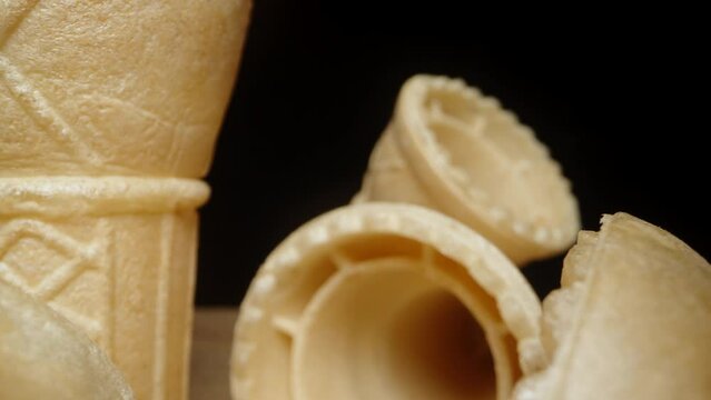 Empty waffle ice cream cones are scattered on the table, and the camera moves through them. Dolly slider extreme close-up.