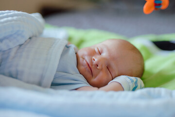 Smiling newborn baby dreaming on the bed