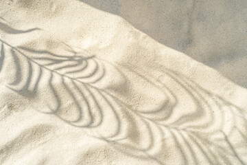 Abstract shadows of tropical leaves leave shadows on the texture of the sand. Abstract texture trendy beige background, nature concept.