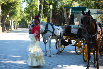 Young black woman dressed as a flamenco gypsy in a famous square in Seville, Spain. She is wearing...