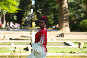 Young black woman dressed as a flamenco dancer stands in a famous park next to the Plaza de España...