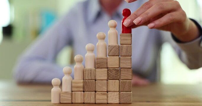 Wooden pawns on steps symbolizing career ladder in company office. Red figurine receiving more privileges on top of career ladder slow motion