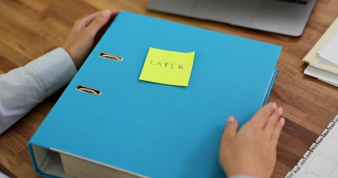 Businesswoman puts sticker with word Later to continue paperwork after coffee break. Manager puts aside pile of paperwork slow motion