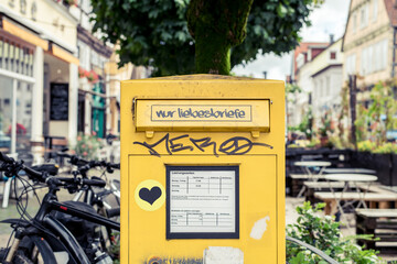 Ein gelber Postkasten wurde mit einem Sticker beklebt, auf dem steht 