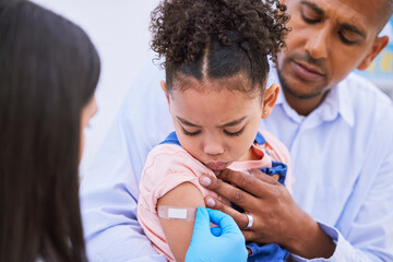 Pediatrician, dad and girl with plaster for vaccine, flu shot or medicine injection in clinic or hospital. Father, kid with bandage and doctor in office for vaccination, consultation and child care. © LuneVA/peopleimages.com