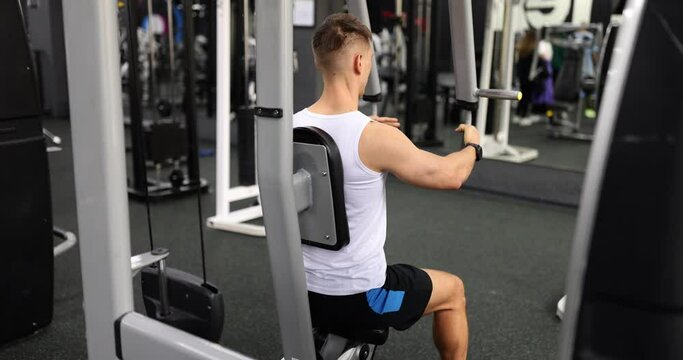 Muscular male athlete doing strength exercises in modern fitness gym. Sportsman testing strength and vitality during training slow motion