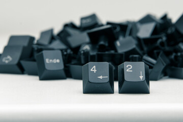 Aus einem Haufen von schwarzen Keyboard-Tasten stechen zwei Zahlen-Tasten hervor: 