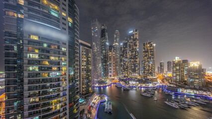 Dubai marina tallest skyscrapers and yachts in harbor aerial day to night timelapse.