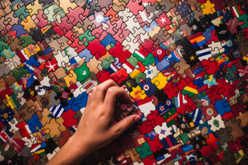 Inspiring image of a hand assembling puzzle pieces, each representing a different country united in peaceful alliance.