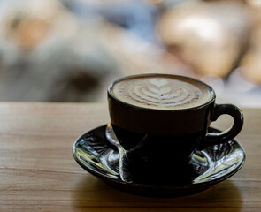 Hot coffee in black cup and blurred nature background.