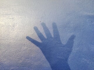 hand silhouette background on blue wall. news illustration concept about asking for help in cases...