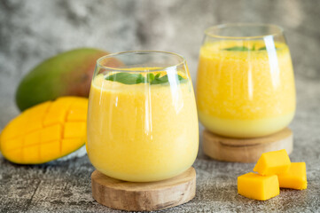 Fresh mango lassi in glasses on grey background with copy space.