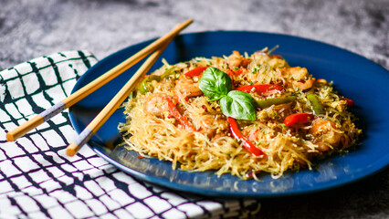 Asian salad with glass noodles, chicken, prawn, shrimp and vegetables on a gray background .