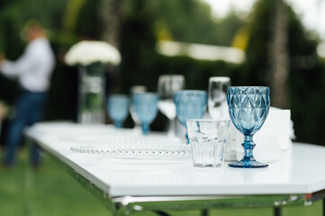 Open -air wedding banquet. The table is decorated with white plates and premium glasses for wine