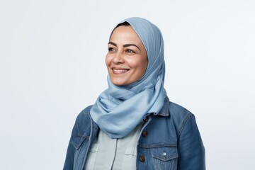 Portrait of a Saudi Arabian woman in her 50s in a white background wearing a denim jacket