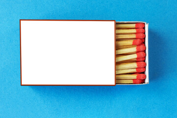 Matchbox with red matchheads on a blue background, top view