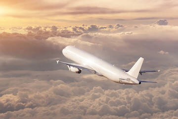 Airplane flies away into the distance at dawn in the sky at sunrise.