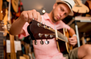 Young musician tuning a classical guitar in a guitar shop