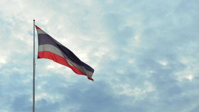 Waving Kingdom of Thailand flag on a pole with blue sky and white clouds on background, high quality 4K slowmotion thai patriotic concept footage. Bangkok, Thailand.