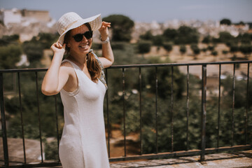 A young woman in a white dress with white hat during tourist visit in Alberobello, Italy