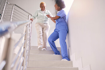 Steps, nurse and help elderly woman, holding hands and assistance in home. Caregiver, stairs and senior African patient walking down, support of person with a disability and kindness in healthcare