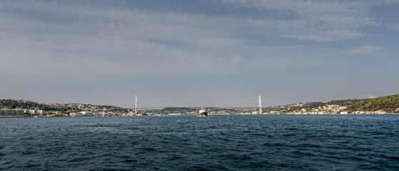 A boat under a bridge in the middle of the Bosforus strait