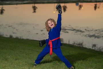 Kid boy in kimono practicing judo, taekwondo, jujitsu, kung-fu, jiu-jitsu, aikido outdoor. Sport...