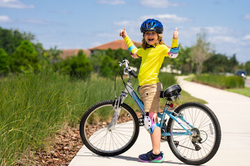 Little kid boy ride a bike in the park. Kid cycling on bicycle. Happy smiling child in helmet...