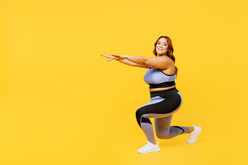 Fototapeta na wymiar Full body sideways young chubby plus size big fat fit woman wear blue top warm up training do squats lunges raise up hands isolated on plain yellow background studio home gym. Workout sport concept.