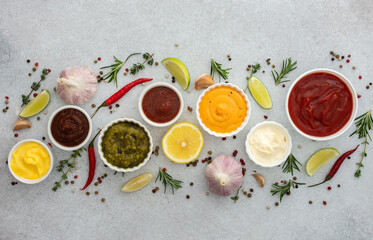 Different types of sauces in bowls with seasonings, rosemary and pepper, thyme and garlic, lime and...