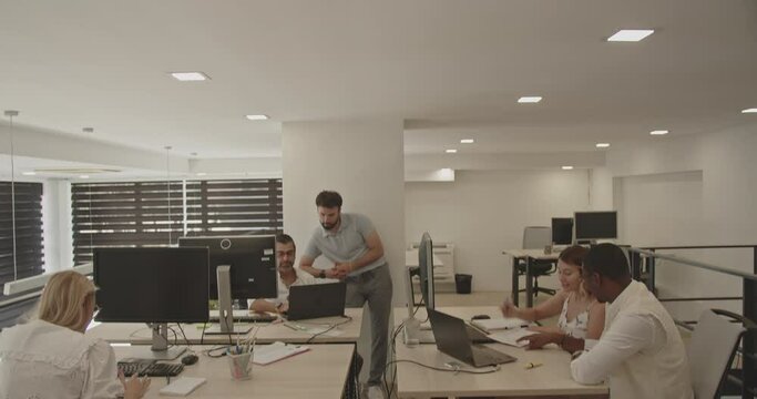 Camera tilt view of various young and senior colleagues, black and Caucasian working together in the office at summertime. Positive work environment concept
