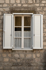Traditional new white window shutters as blinds on old stone home